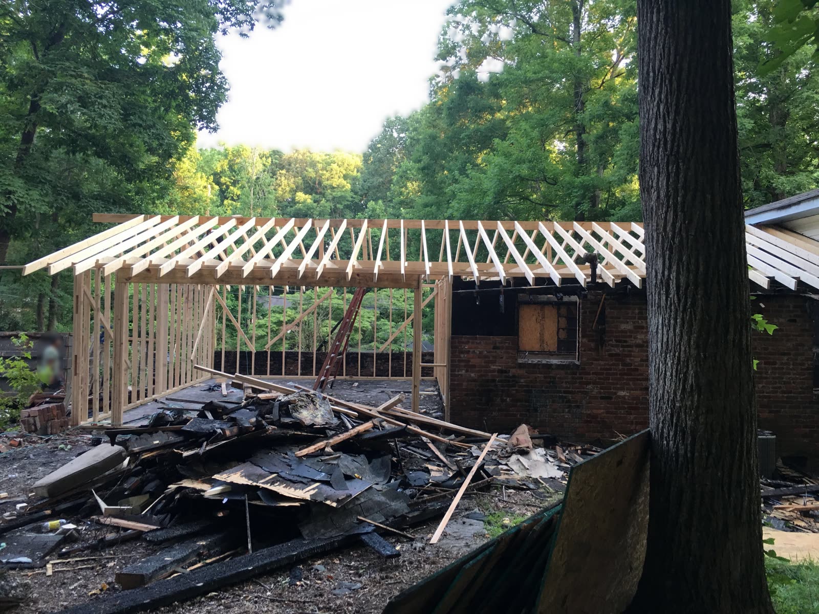 New roof framing going up over a room addition on a brick home